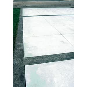 Concrete driveway panels separated by tooled control joints with a dark stamped border